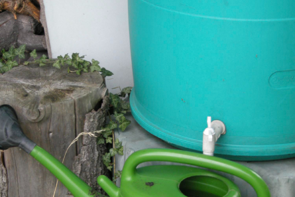 waterbesparende blauwe regenton met kraantje en groene gieter eronder