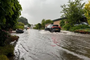 auto rijdt in water door overstroomde straat